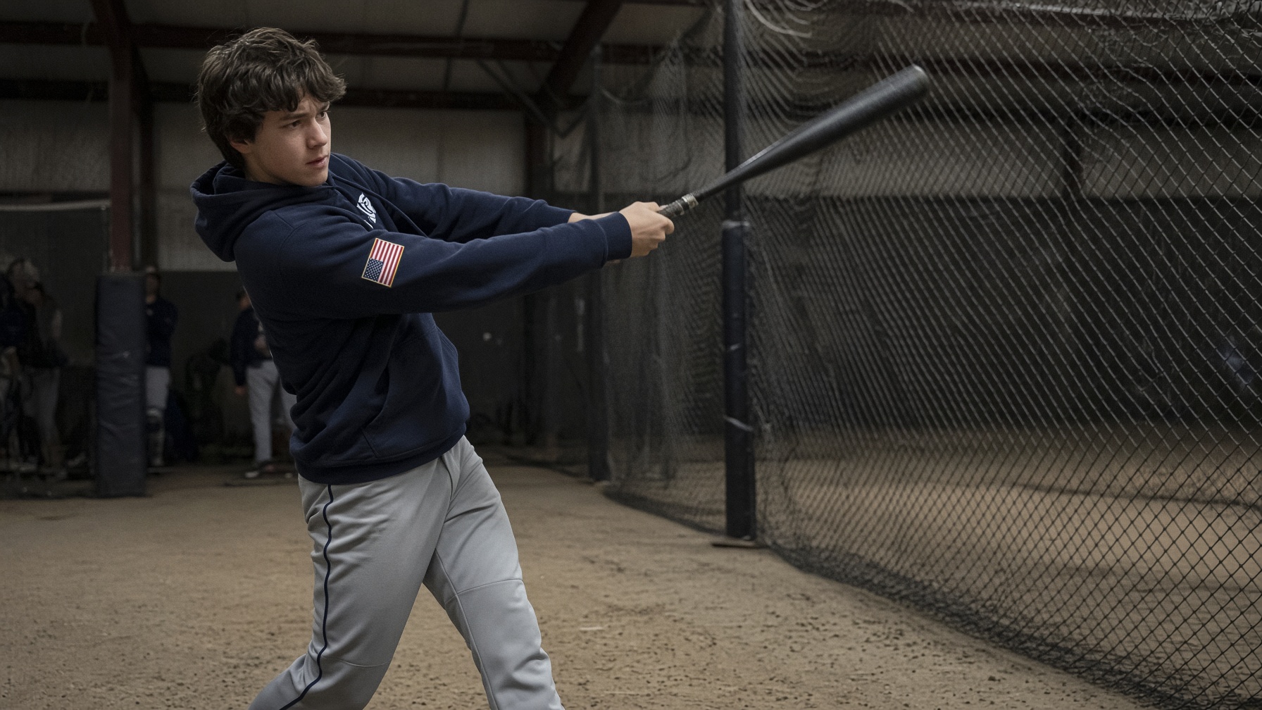 Young baseball athlete training in an indoor cage