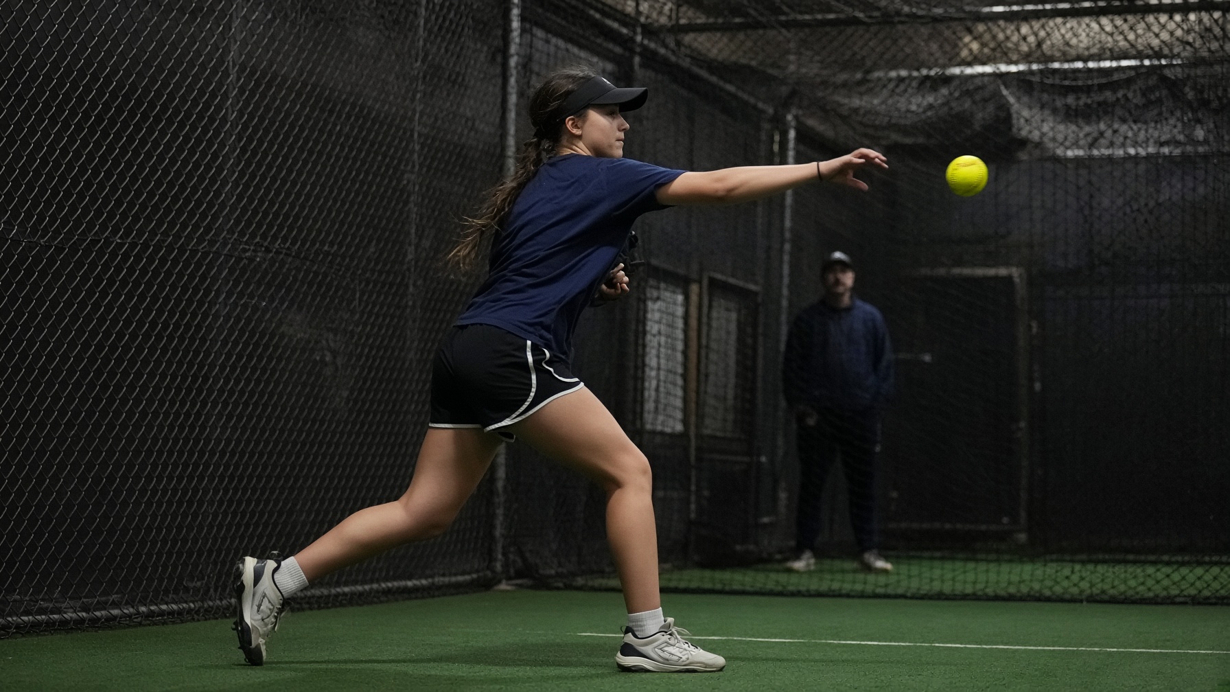Fastpitch athlete throwing in an indoor training space